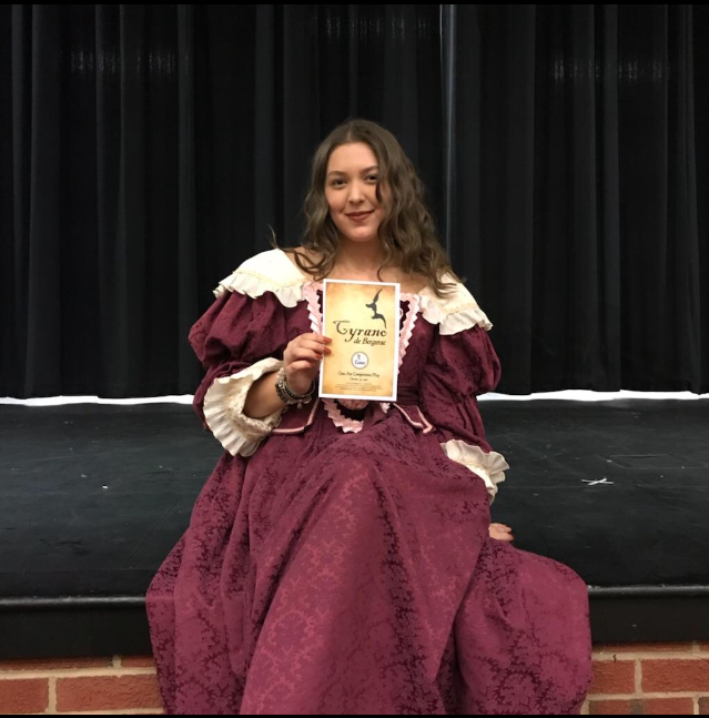 Roxane, played by Alexia Stearns, poses with a program.